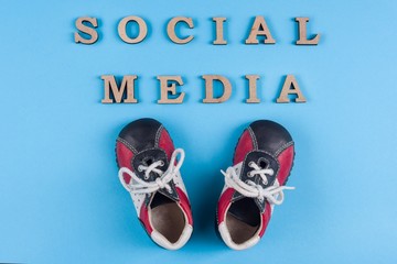 Text social media abstract wooden letters. Blue background with baby sneakers. People connecting and sharing social media