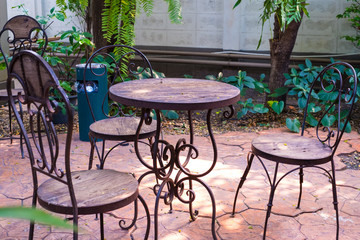 Fototapeta premium Steel chairs and tables with wooden seat and tree on stone floor in the garden