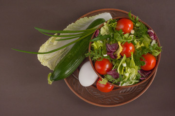 Healthy food - arugula salad with iceberg, cherry tomatoes, chinese and red cabbage near ingredients