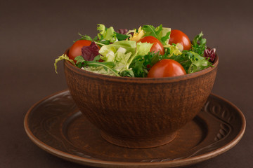 Clay dish full of organic food - salad with iceberg, arugula, cherry tomatoes, chinese and red cabbage close up