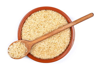 Integral, long grain brown rice pile in porcelain bowl with wooden spoon isolated on white background, top view