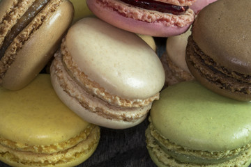 Macarons de couleurs différentes en tas sur fond noir