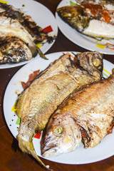 fresh fried baked fish with scales and lemon in a plate