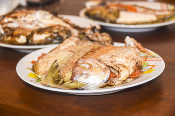 fresh fried baked fish with scales and lemon in a plate