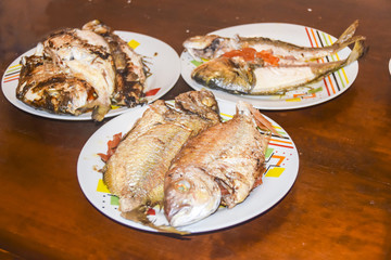 fresh fried baked fish with scales and lemon in a plate