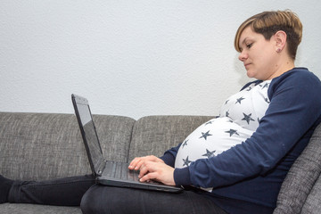 Schwangere Frau arbeitet an einem Laptop