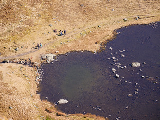 Aerial view of Bowscale Tarn with hikers, walkers relaxing beside it in the English Lake District, UK.