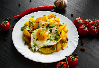 fried egg with potato in a plate on dark wooden background