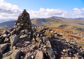The summit cairn (pile of stones) of Carrock Fell with Bowscale Fell and Blencathra in the distance in the English Lake District, UK.