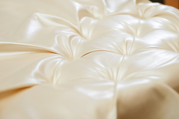Close-up of beige leather in the tailoring workshop. Makes a classic bed with capitone. Use for furniture crafting, fashion design and interior design.