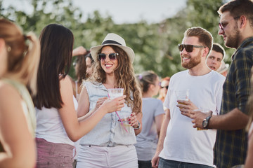 Group of people standing and drinking at the summer outdoor party 