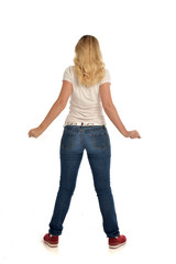 full length portrait of blonde girl wearing simple white shirt and jeans, standing pose, isolated on white studio background.