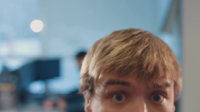 Cute guy in denim shirt with blond hair throwing ball during lunch break. Guy is breaking something in office. Indoors. Close-up.
