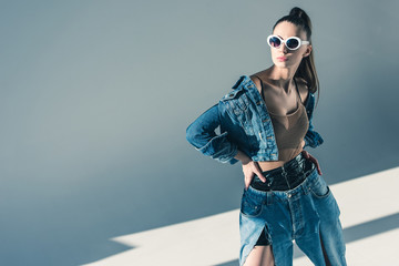 fashionable brunette model posing in denim style and sunglasses - obrazy, fototapety, plakaty