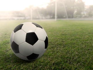 Soccer ball on a grass football field, under the sunset