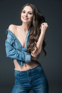 smiling seductive woman posing in denim shirt, isolated on grey