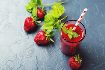 Fresh strawberry smoothie in a glass on black background.