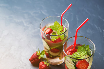Cold and refreshing infused detox water with strawberry and cucumber in glass on black background.