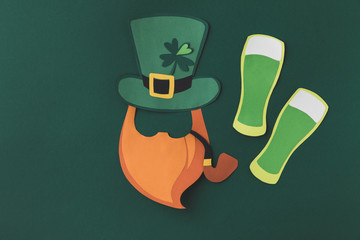 top view of paper decoration of smoking leprechaun and beer for st patricks day isolated on green