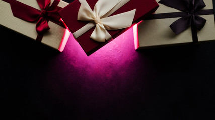 luxury mystery presents on dark background. glowing light. elegant sophisticated party gift boxes to celebrate holiday. free space concept