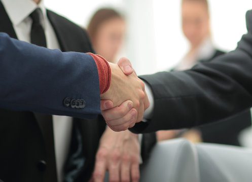 Partners concluding deal and shaking hands in the presence of team members