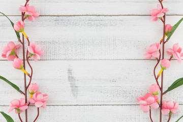Fake pink flower branches on white wood background with copy space
