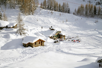 Paesaggio di montagna con baite innevate sulle piste da sci 
