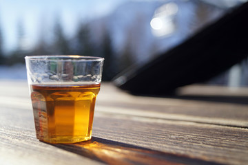 Bicchiere di grappa barricata crea una lunga ombra sul tavolo di legno di una baita in montagna 