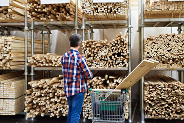 Man chooses and buys wooden boards in store