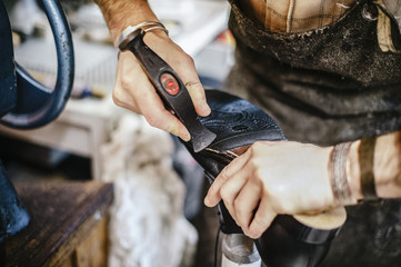 shoemaker adjusts shoe sole in his workshop