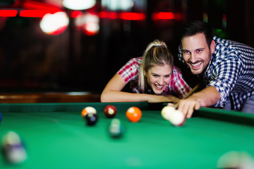 Young couple playing snooker together in bar