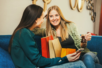 Two happy women are sitting in cafe and planing shopping. 