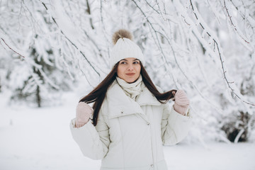 Fototapeta na wymiar A beautiful and fashoin woman in white warm clothing walking in snowy weather.