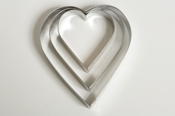 A set of three heart shaped cookie cutters on a white background