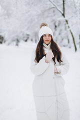 A beautiful and fashoin woman in white warm clothing walking in snowy weather.