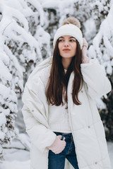 A beautiful and fashoin woman in white warm clothing walking in snowy weather.