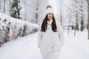 Fototapeta na wymiar A beautiful and fashoin woman in white warm clothing walking in snowy weather.
