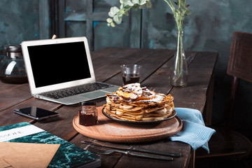 Laptop and pancakes with juice. Healthy breakfast