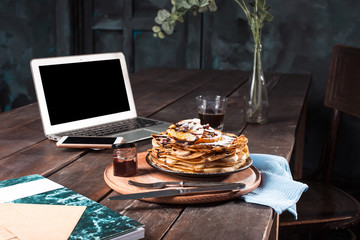 Laptop and pancakes with juice. Healthy breakfast