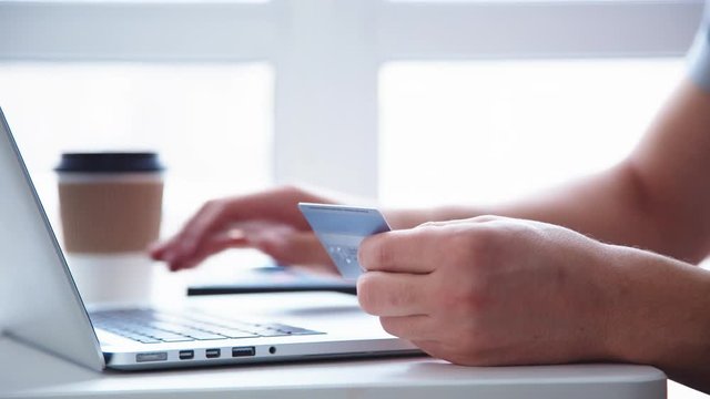 Side view of man using credit card for online shoping