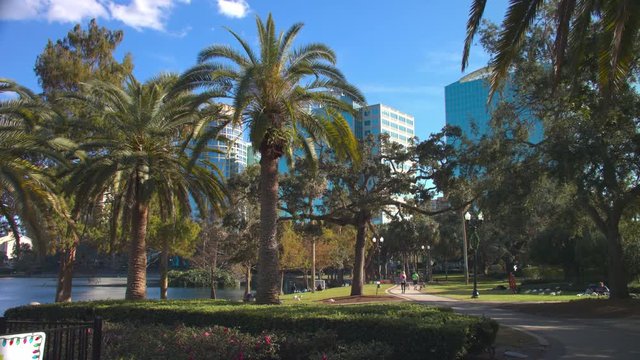 Picturesque Lake Eola Park in Orlando FL City Center with People Enjoying Good Weather surrounded by Palm Trees and Downtown Buildings on a Sunny Day in Central Florida