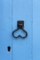 Heart shaped door handle on an old blue painted door