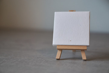 blank mini canvas on easel on dark background – customizable for individiual notes - obrazy, fototapety, plakaty