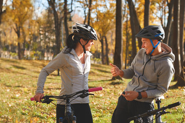 Happy young couple having fun riding a bicycle on sunny autumn day in the park.