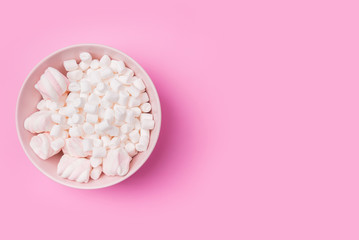 White Fluffy white marshmallows in bowl isolated on pink background. Top view image. Copyspace for your text