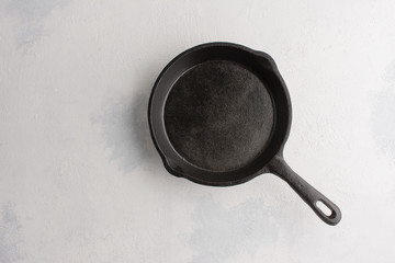 empty black cast iron drip pan on light concrete background. idea for menu or recipe or for...