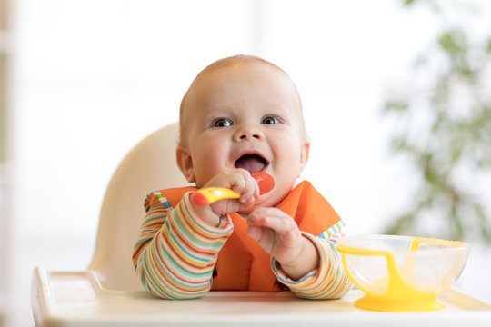 happy baby boy waiting for food with spoon at table