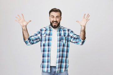 Naklejka premium Portrait of angry insane european man, shouting and spreading his hands while gesturing, over gray background. I borrowed you guitar for one day and you managed to broke it