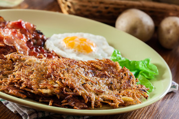 Hash browns. Potato pancakes with crispy fried bacon and fried egg