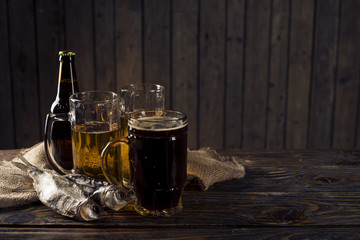 glass of beer, salted fish and nuts on a wooden table